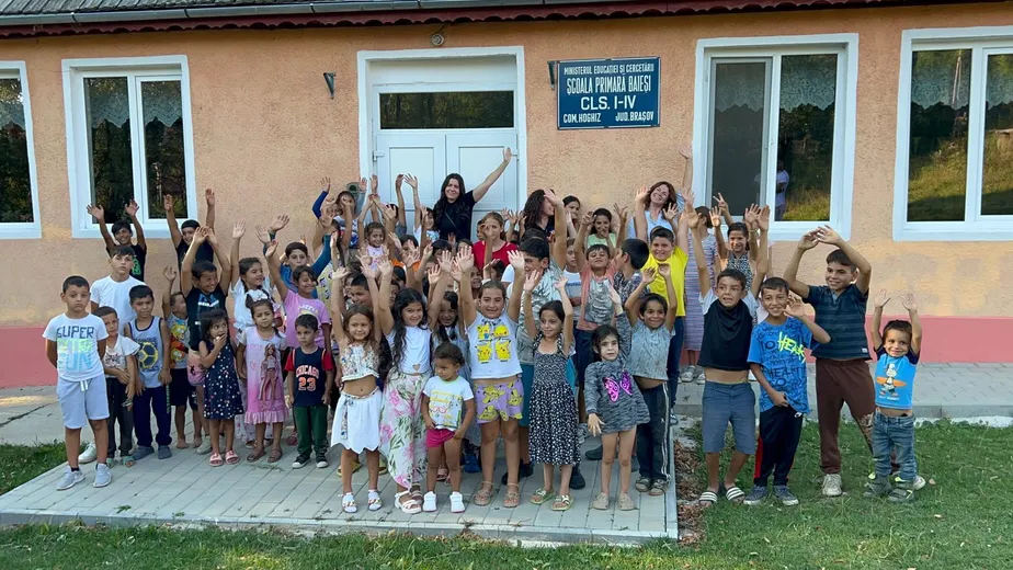 Copii cu mâinile ridicate, sărbătorind în fața școlii